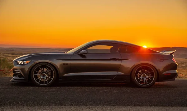 Amplio plano de un coche negro en una carretera al atardecer — Foto de Stock