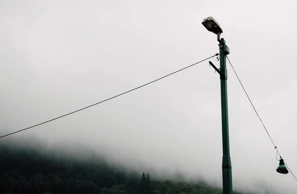 Farola de metal en el campo durante un día neblinoso y sombrío —  Fotos de Stock