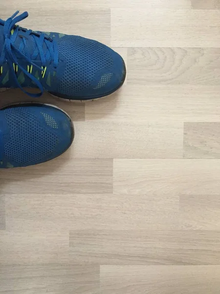 Tiro vertical de um par de sapatos de corrida azuis em uma superfície de madeira — Fotografia de Stock