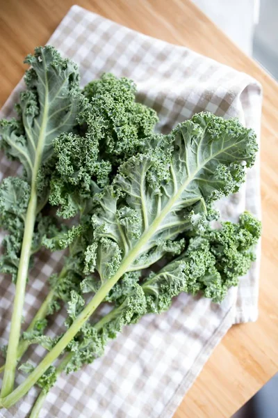 Closeup shot of a bunch of Kale or leaf cabbage leaves on a cloth and a wood surface — Stok Foto
