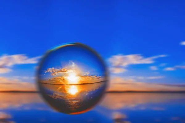 Fotografia creativa palla lente della luce solare all'orizzonte con nuvole intorno nel cielo blu — Foto Stock