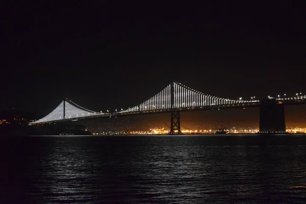 夜间在加州旧金山的水面上拍摄的一座被点燃的海湾大桥 — 图库照片