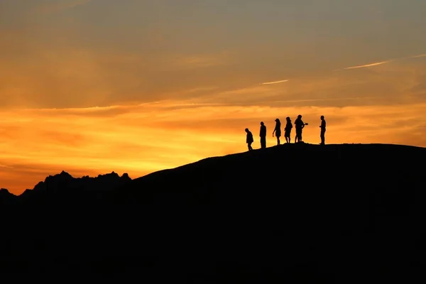 Silhouette shot of people on a hill during sunset — Stock Photo, Image