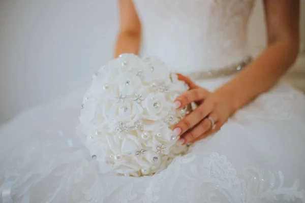 Gros plan de la mariée dans une robe blanche tenant un bouquet de fleurs blanches — Photo