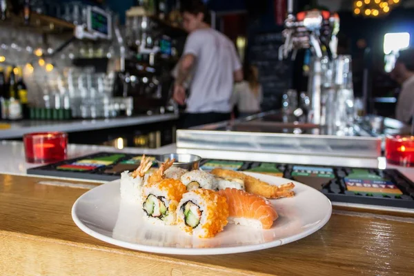 Nahaufnahme von Sushi-Rollen auf einem weißen Teller auf dem Tresen mit verschwommenem Hintergrund — Stockfoto