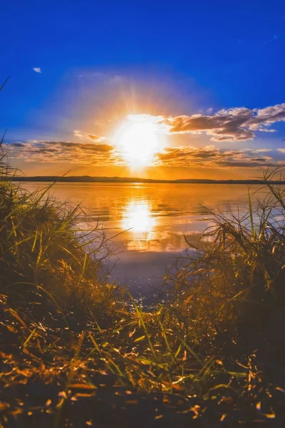 Vertikální záběr krásného jezera se sluncem jasně zářícím na zamračené obloze — Stock fotografie