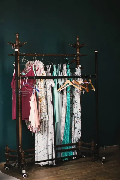 Vertical shot of brown clothes hangers and colorful clothes hanged on a rack