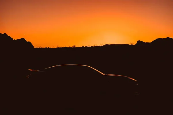 Silhouette di una potente auto sportiva muscolare fresca in un deserto all'alba — Foto Stock