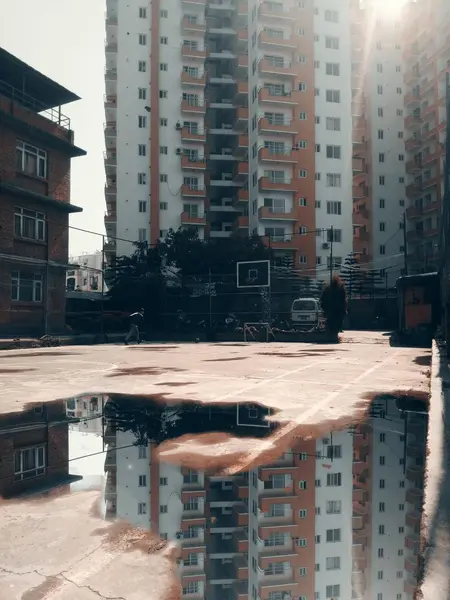 Vertikale Aufnahme von Wasser auf der Straße, das tagsüber die Gebäude in der Ferne reflektiert — Stockfoto