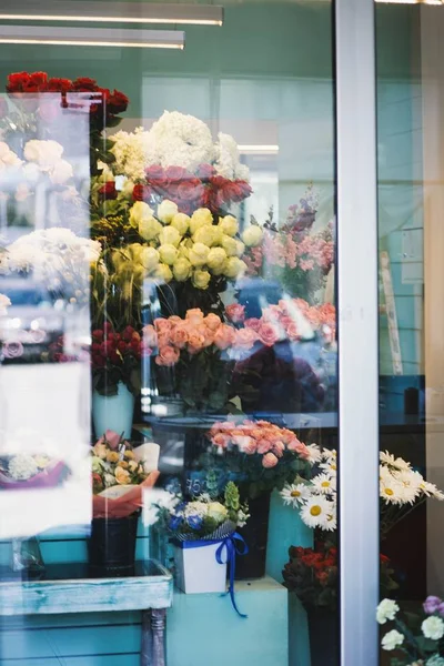 Çiçekçinin içindeki vazolarda farklı renklerde çeşitli çiçeklerin dikey çekimi — Stok fotoğraf