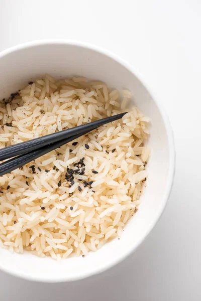 Closeup shot of cooked rice in a white plastic bowl with chopsticks on it on a white background — Stock Photo, Image