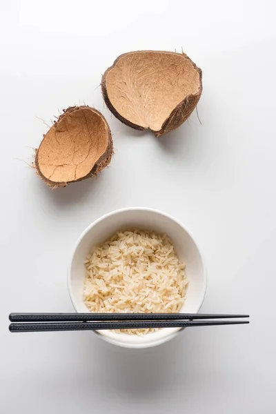 Closeup shot of cooked rice in a white plastic bowl with chopsticks on it on a white background — Stock Photo, Image