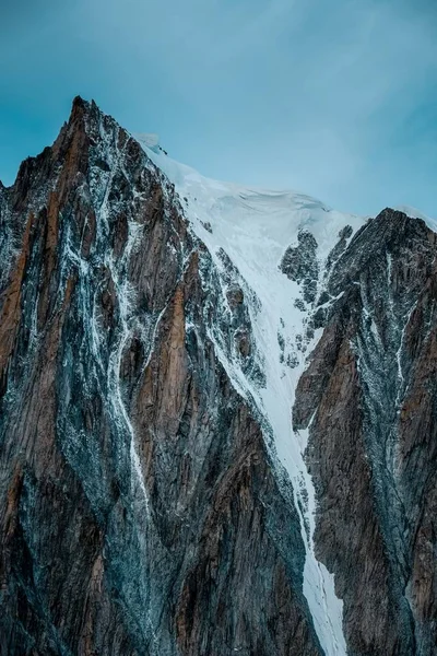 Verticale opname van een besneeuwde berg met een heldere lucht op de achtergrond — Stockfoto