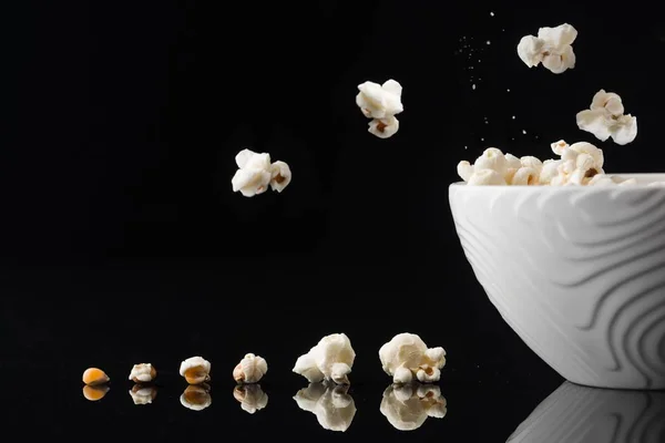 Primer plano de un tazón blanco con palomitas de maíz en un fondo oscuro — Foto de Stock
