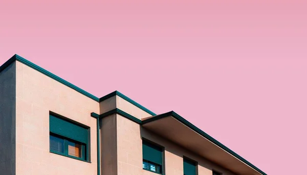 Captura de ángulo bajo de una parte superior de los edificios con un fondo rosa claro — Foto de Stock
