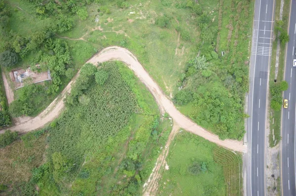 Tiro aéreo de uma estrada estreita no campo com um belo campo à esquerda — Fotografia de Stock