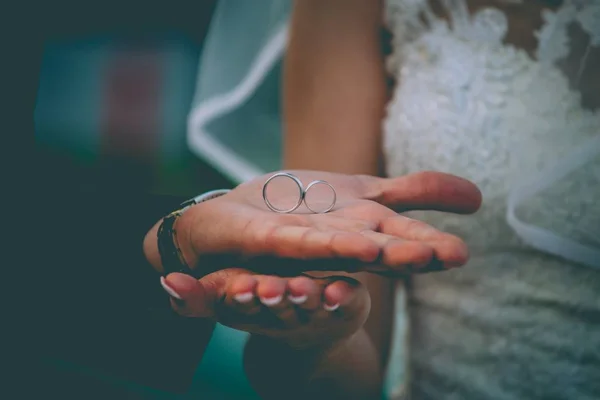 Close-up de uma noiva e um noivo segurando anéis de capina lá com um fundo borrado — Fotografia de Stock