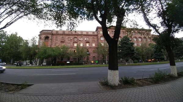 Тропинка рядом с деревьями и улицей со зданием вдали в Армении — стоковое фото