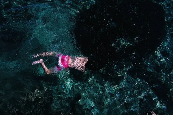 분홍색과 흰색 수영복을 입은 사람이 맑은 바다에서 수영하는 모습을 넓게 찍은 사진 — 스톡 사진