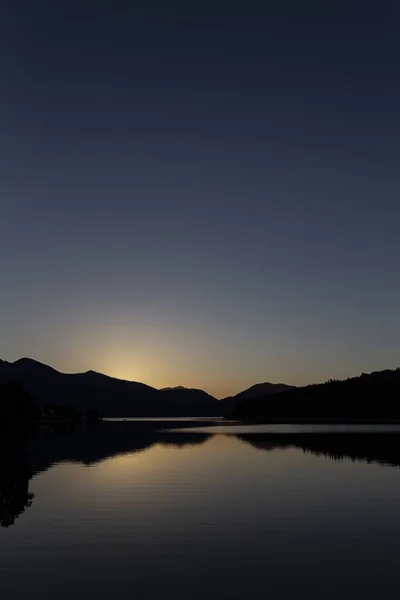 Vertikalt Silhuettbilde Fjell Ved Siden Vann Solnedgang – stockfoto