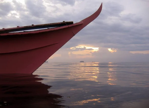 Primo piano di una barca rosa scuro sul corpo d'acqua sotto un cielo nuvoloso — Foto Stock