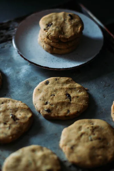 Verticale selectieve close-up shot van gebakken koekjes op een bord en op de tafel — Stockfoto