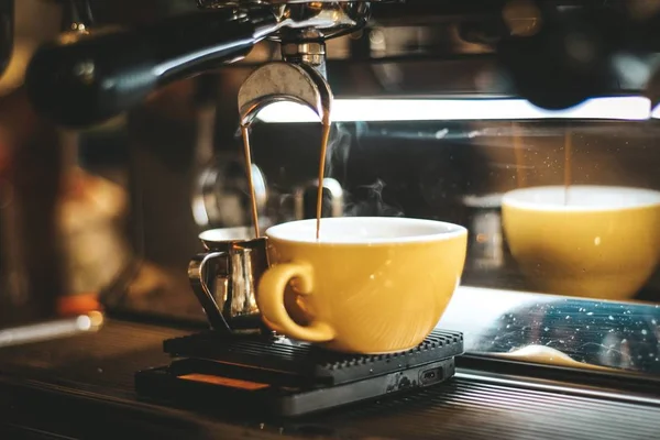 Szelektív Vértes shot kávét öntés le egy sárga kerámia csésze egy eszpresszó gép — Stock Fotó