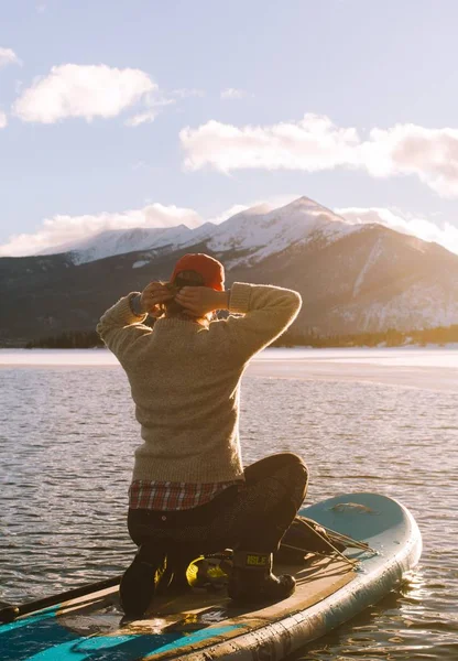 Hona på en Paddleboard på vattenfast ställande hennes hår med berg i fjärran på dagtid — Stockfoto