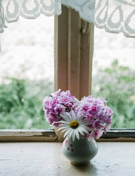 Vertikale selektive Aufnahme rosa und weißer Blüten in einer Vase auf der Fensterbank — Stockfoto