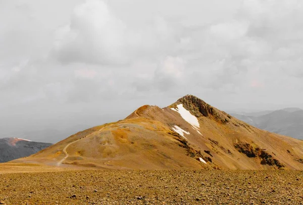 Όμορφη βολή ένα χωράφι με ένα βουνό στην απόσταση κάτω από ένα συννεφιασμένο ουρανό — Φωτογραφία Αρχείου