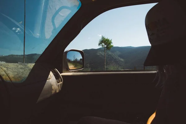 昼間の森の山々を眺めながら車の中に座っている女性の美しいショット — ストック写真