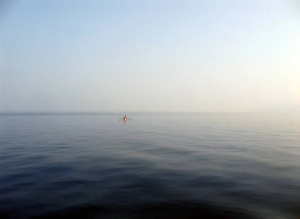 在晴朗的天空下，在平静的海面上漂浮着一艘小船的广角镜头 — 图库照片