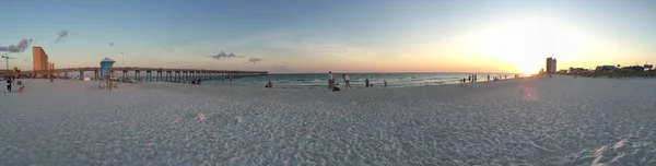 Panoramic shot of people on the beach shore with a beautiful sky in the background — Stock Photo, Image