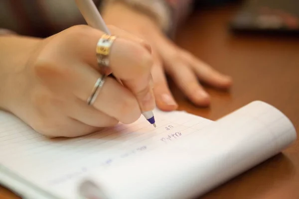 Közelkép egy nőstény tolláról, ahogy ír valamit egy tankönyvbe. — Stock Fotó