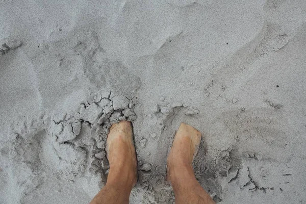 Tiro aéreo dos pés de uma pessoa em uma areia — Fotografia de Stock