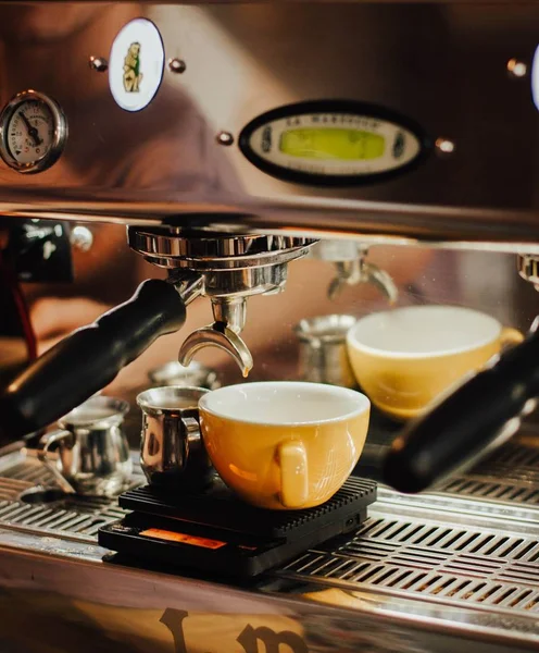Vértes lövés kávét ömlött le egy sárga kerámia csésze egy eszpresszó gép — Stock Fotó