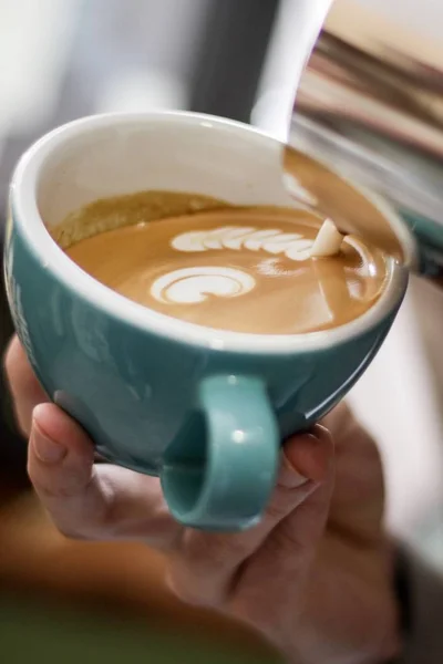 Vertikale selektive Nahaufnahme von Kaffee mit Latte Art in einer blauen Keramiktasse auf einer Holzoberfläche — Stockfoto