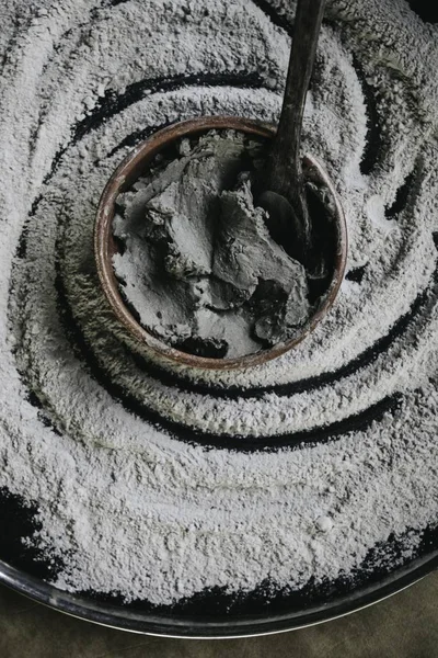 Closeup shot of a ceramic cooking pot with ingredients and a spoon in it with flour around — Stock Photo, Image