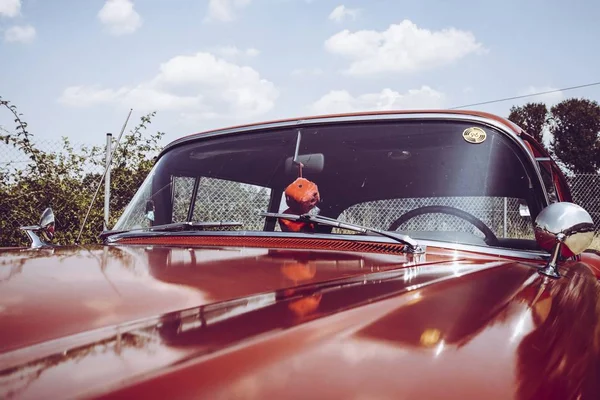 Primer plano de un coche de músculo rojo con un dado colgando del espejo de un coche durante el día — Foto de Stock