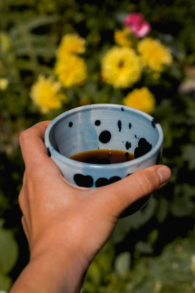 Primer plano selectivo vertical de una persona sosteniendo una taza de cerámica con té —  Fotos de Stock