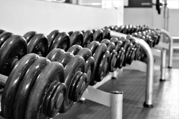 Cerrar plano de pesas de gimnasio en el estante con fondo borroso en blanco y negro — Foto de Stock