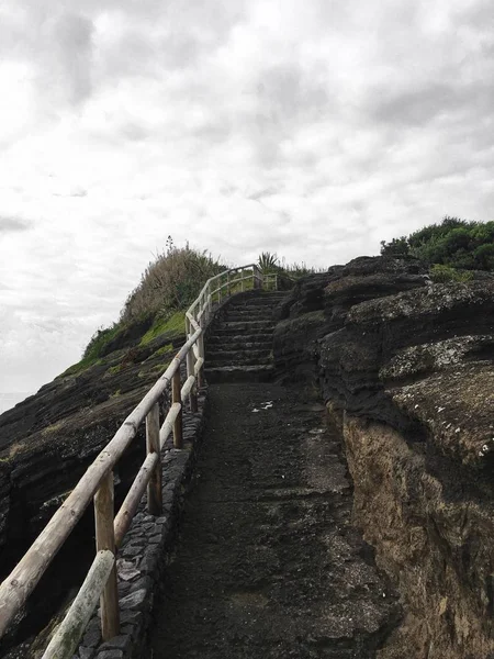 Stone stairway towards the top of the hill with wooden railing under cloudy gray sky after the rain — Stock Photo, Image