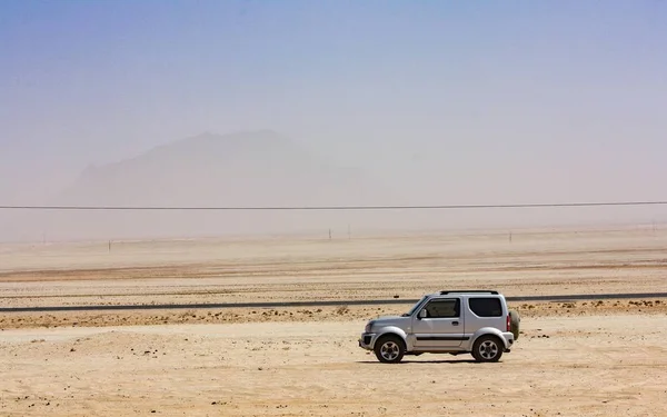 Schöne Aufnahme eines Autos, das an einem sonnigen Tag in einer Wüste mit klarem Himmel im Hintergrund geparkt ist — Stockfoto