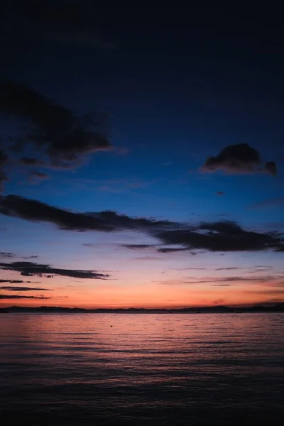 Bela paisagem do mar ao pôr do sol com nuvens escuras e reflexão na água calma — Fotografia de Stock