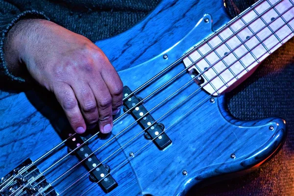 Closeup shot of musician hands playing the blue bass guitar — Stock Photo, Image
