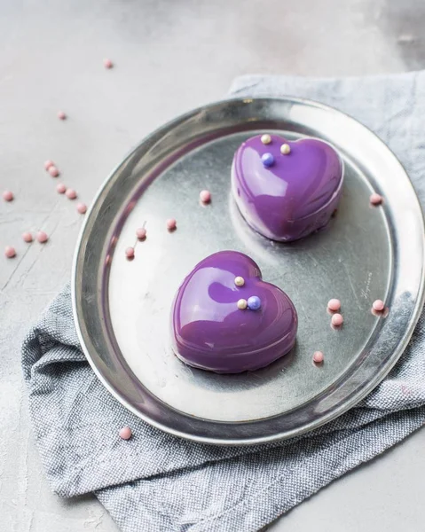 Vertical selective closeup shot of purple dessert in the shape of hearts on a gray oval tray — Stock Photo, Image