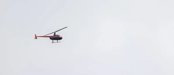 Panoramic shot of a helicopter flying in a cloudy sky — Stock Photo, Image