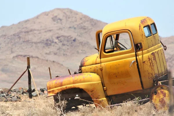 Nära skott av en gammal trasig gul lastbil i en torr gräsbevuxen fält med en suddig bakgrund — Stockfoto