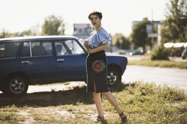 Foco raso tiro de um modelo feminino atraente em um vestido off-shoulder posando perto de um veículo — Fotografia de Stock