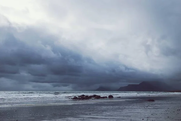 Beautiful shot of the foggy sea with cliffs and hills on the side and amazing clouds in the sky